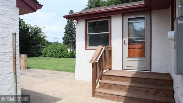 6007 Vincent Ave N, Brooklyn Center, MN 55430 - view of exterior entry with stucco siding, a yard, and a patio
