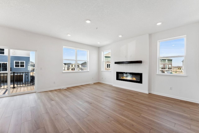 2700 Kepler Ave NE, Saint Michael, MN 55376 - unfurnished living room featuring wood finished floors, recessed lighting, a glass covered fireplace, and a textured ceiling