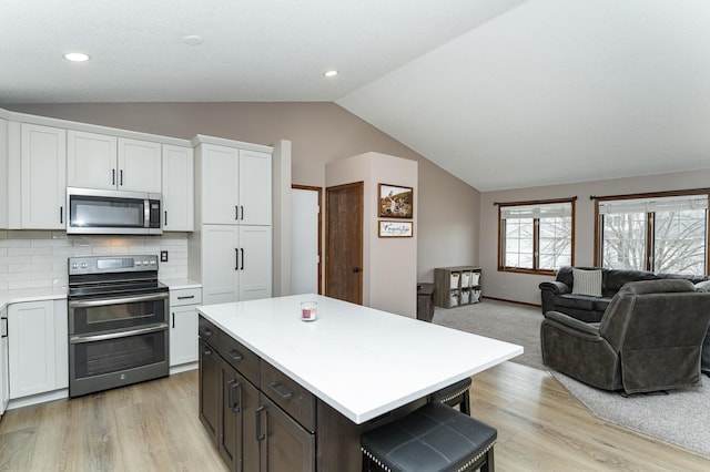 3415 Lake St NW, Rochester, MN 55901 - kitchen featuring stainless steel appliances, lofted ceiling, light countertops, light wood finished floors, and white cabinets