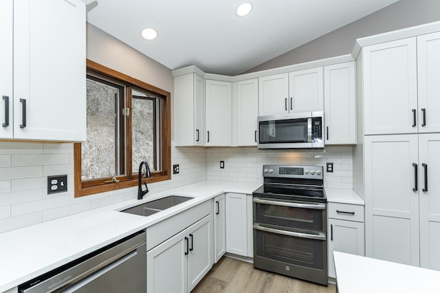 3415 Lake St NW, Rochester, MN 55901 - kitchen featuring appliances with stainless steel finishes, vaulted ceiling, light countertops, white cabinets, and recessed lighting