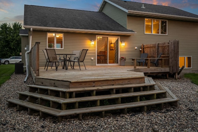 133 Uriah Ct, Mankato, MN 56001 - back of property at dusk with outdoor dining area, a wooden deck, and roof with shingles