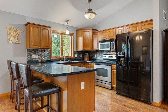 133 Uriah Ct, Mankato, MN 56001 - kitchen featuring appliances with stainless steel finishes, a peninsula, tasteful backsplash, vaulted ceiling, and pendant lighting
