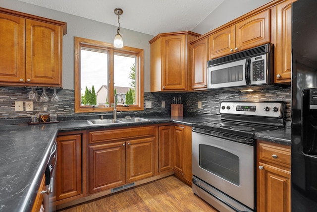 133 Uriah Ct, Mankato, MN 56001 - kitchen with appliances with stainless steel finishes, brown cabinets, tasteful backsplash, and dark countertops