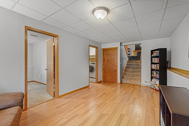 133 Uriah Ct, Mankato, MN 56001 - unfurnished living room featuring washer / clothes dryer, light wood finished floors, stairway, and a drop ceiling