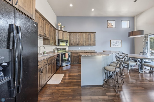 5543 Tuscan Ct S, Fargo, ND 58104 - kitchen with black appliances, dark wood-style floors, a center island, recessed lighting, and a breakfast bar area