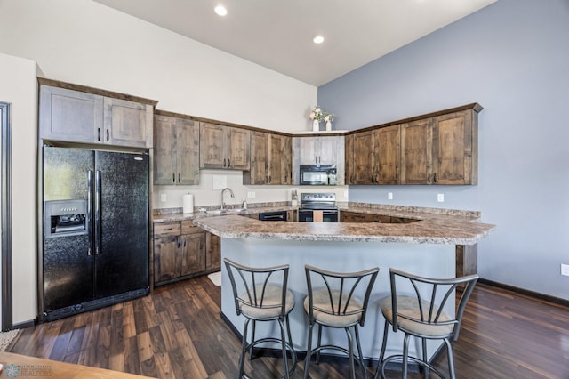 5543 Tuscan Ct S, Fargo, ND 58104 - kitchen featuring black appliances, dark wood-style flooring, a breakfast bar area, recessed lighting, and high vaulted ceiling
