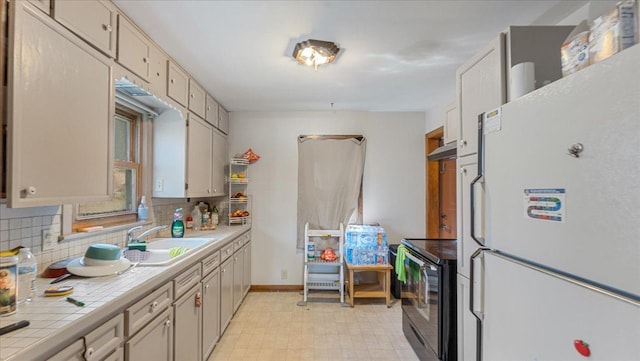 806 8th St SW, Willmar, MN 56201 - kitchen featuring freestanding refrigerator, electric range, tile countertops, backsplash, and light floors