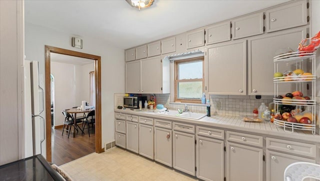 806 8th St SW, Willmar, MN 56201 - kitchen featuring tasteful backsplash, stainless steel microwave, freestanding refrigerator, and light wood-style floors