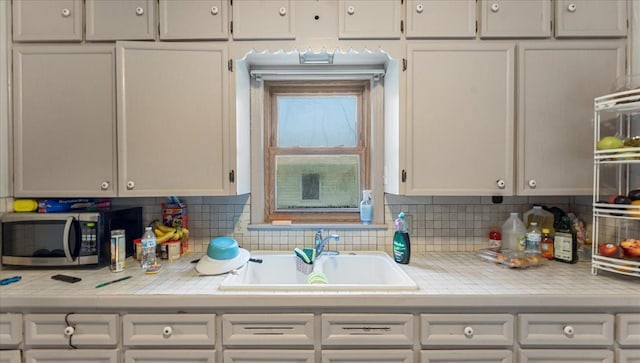 806 8th St SW, Willmar, MN 56201 - kitchen with stainless steel microwave, light countertops, decorative backsplash, and white cabinets