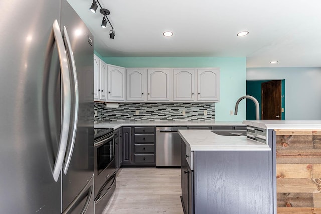 1607 Pleasant View Dr, North Mankato, MN 56003 - kitchen with stainless steel appliances, light wood finished floors, backsplash, a peninsula, and white cabinets