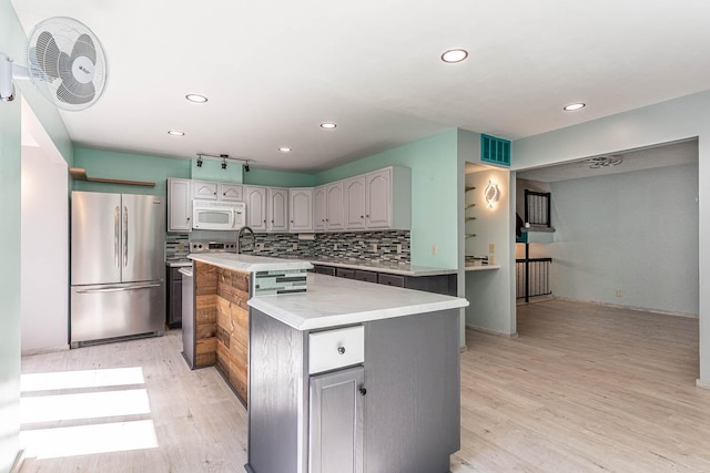 1607 Pleasant View Dr, North Mankato, MN 56003 - kitchen with freestanding refrigerator, white microwave, an island with sink, light wood-style floors, and light countertops