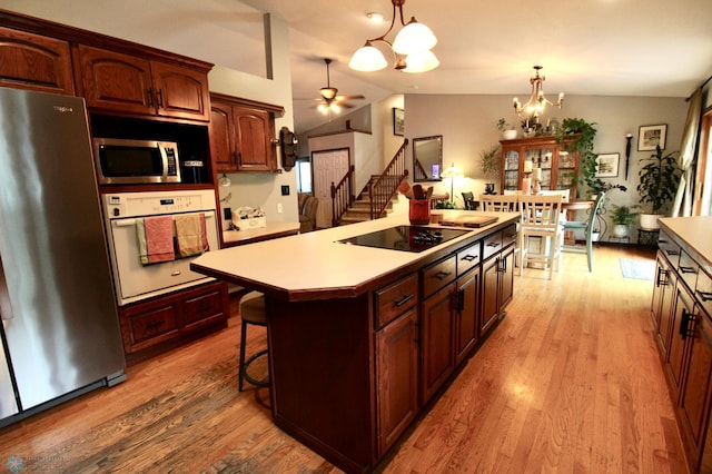 1307 Libra Ln, Fargo, ND 58104 - kitchen with stainless steel appliances, a chandelier, light wood-style flooring, a kitchen island, and vaulted ceiling