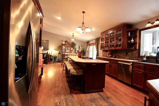 1307 Libra Ln, Fargo, ND 58104 - kitchen featuring stainless steel appliances, a kitchen island, wood finished floors, a chandelier, and a kitchen breakfast bar