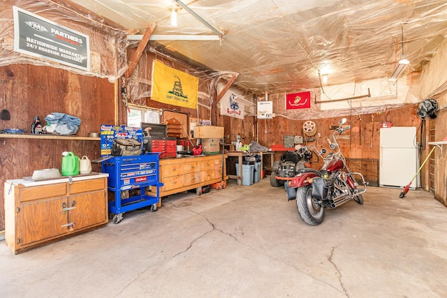 41793 Kilkenny Rd, Kilkenny, MN 56052 - garage with freestanding refrigerator, a workshop area, and wood walls