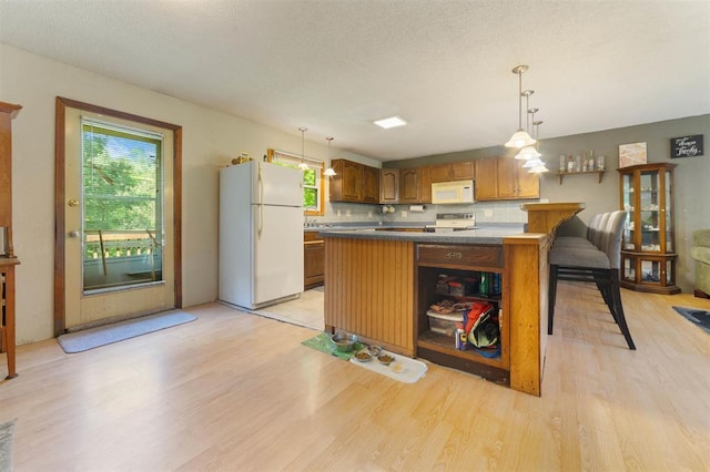 4043 Rehbein Rd, Duluth, MN 55803 - kitchen featuring white appliances, light wood finished floors, brown cabinets, a kitchen island, and a textured ceiling