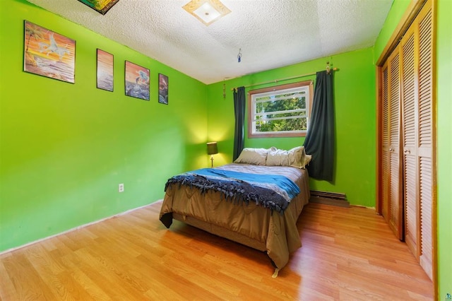 4043 Rehbein Rd, Duluth, MN 55803 - bedroom with wood finished floors, a textured ceiling, a closet, and a baseboard radiator