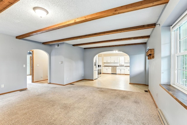 453 Van Dyke St, Saint Paul, MN 55119 - unfurnished living room with arched walkways, beamed ceiling, light carpet, plenty of natural light, and a textured ceiling