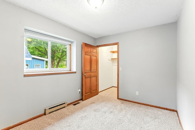 453 Van Dyke St, Saint Paul, MN 55119 - unfurnished bedroom featuring a baseboard heating unit, a textured ceiling, carpet flooring, and a spacious closet