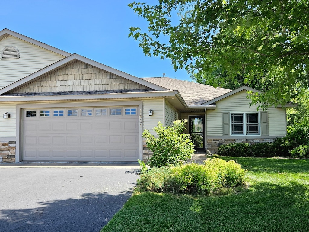 1411 Blue Jay Pl, New Richmond, WI 54017 - ranch-style home featuring stone siding, an attached garage, driveway, and a front lawn