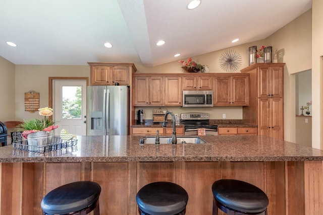 2045 Roberta Dr, North Mankato, MN 56003 - kitchen with appliances with stainless steel finishes, lofted ceiling, recessed lighting, a kitchen bar, and brown cabinetry