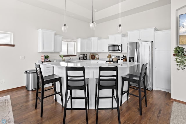 1592 69th Ave S, Fargo, ND 58104 - kitchen with appliances with stainless steel finishes, a center island, a breakfast bar, white cabinetry, and a high ceiling