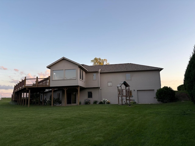 53030 254th Ave, Plainview Twp, MN 55964 - back of property at dusk with a lawn, a deck, an attached garage, and roof with shingles