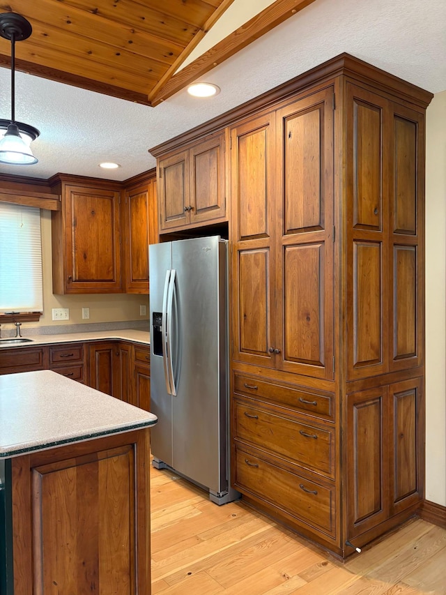 53030 254th Ave, Plainview Twp, MN 55964 - kitchen featuring stainless steel fridge with ice dispenser, light wood finished floors, light countertops, brown cabinets, and decorative light fixtures