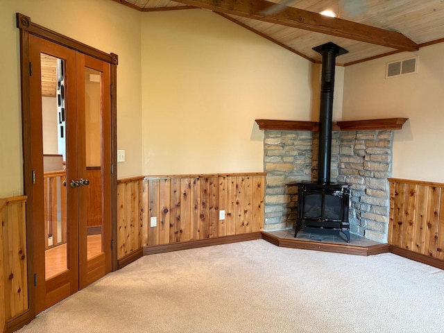 53030 254th Ave, Plainview Twp, MN 55964 - unfurnished living room featuring a wood stove, a wainscoted wall, wood ceiling, carpet flooring, and wooden walls