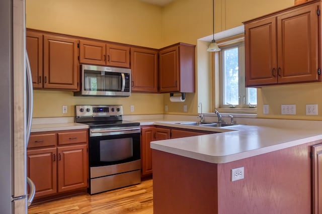 20730 Glenbrook Ave N, Forest Lake, MN 55025 - kitchen with appliances with stainless steel finishes, a peninsula, light countertops, pendant lighting, and light wood-style flooring