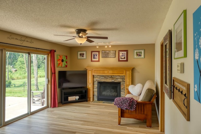 20730 Glenbrook Ave N, Forest Lake, MN 55025 - living area featuring a textured ceiling, a ceiling fan, a stone fireplace, and light wood-style flooring