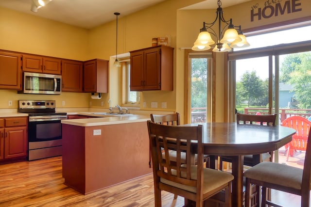 20730 Glenbrook Ave N, Forest Lake, MN 55025 - kitchen featuring appliances with stainless steel finishes, a chandelier, light countertops, a peninsula, and light wood-type flooring