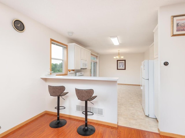 17625 48th Pl N, Plymouth, MN 55446 - kitchen with white appliances, white cabinets, a peninsula, light countertops, and a breakfast bar area