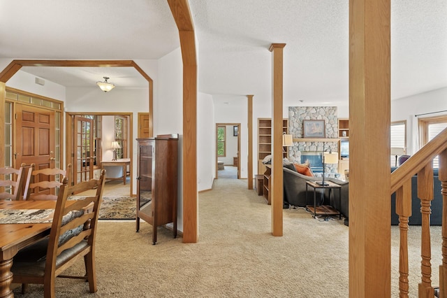 11691 115th St N, Grant, MN 55082 - dining space with light colored carpet, a textured ceiling, a stone fireplace, and arched walkways