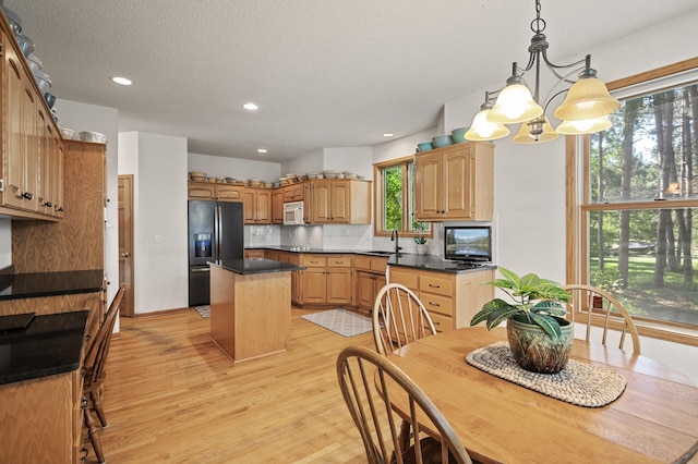 11691 115th St N, Grant, MN 55082 - kitchen featuring refrigerator with ice dispenser, light wood-style floors, a kitchen island, dark countertops, and recessed lighting