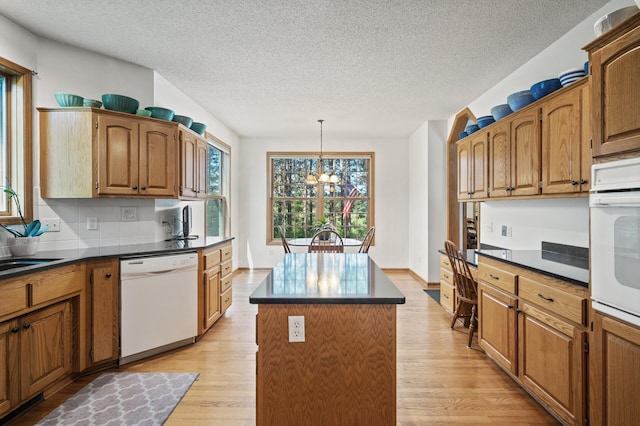 11691 115th St N, Grant, MN 55082 - kitchen featuring white appliances, a center island, light wood-style flooring, dark countertops, and a chandelier