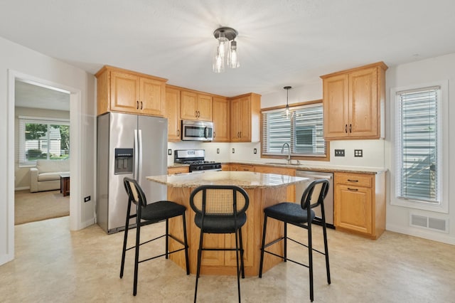5737 20th Ave S, Minneapolis, MN 55417 - kitchen with appliances with stainless steel finishes, a kitchen island, a kitchen breakfast bar, light stone countertops, and light brown cabinets