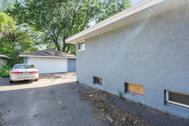 2813 Ohenry Rd, Brooklyn Center, MN 55430 - view of side of home with stucco siding, a detached garage, and an outbuilding