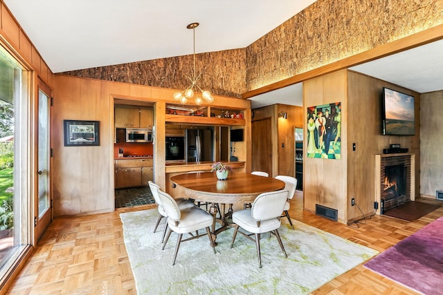 789 Viking Dr E, Little Canada, MN 55117 - dining area featuring high vaulted ceiling, wood walls, a warm lit fireplace, and a chandelier
