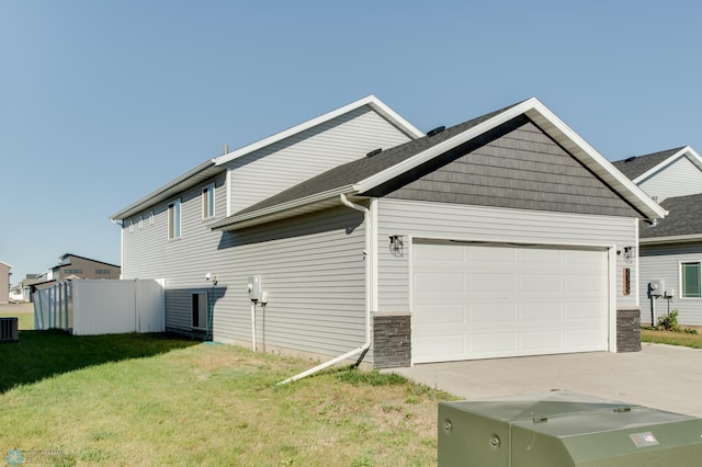 7339 24th St S, Fargo, ND 58104 - view of home's exterior featuring an attached garage, driveway, a lawn, and stone siding