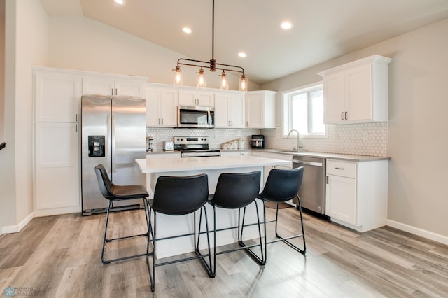 7339 24th St S, Fargo, ND 58104 - kitchen featuring stainless steel appliances, white cabinets, lofted ceiling, a kitchen island, and light countertops
