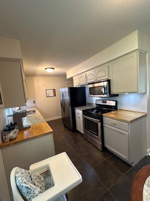 5025 Wilshire Blvd, Crystal, MN 55429 - kitchen with stainless steel appliances, dark tile patterned flooring, a textured ceiling, and butcher block counters