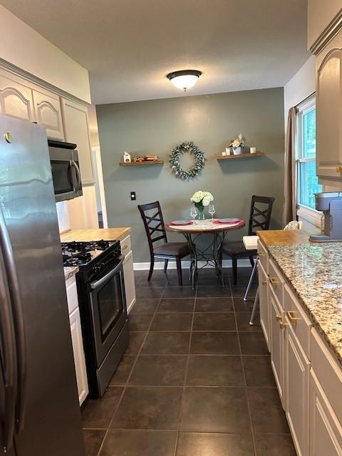 5025 Wilshire Blvd, Crystal, MN 55429 - kitchen with stainless steel appliances, dark tile patterned floors, light stone countertops, and open shelves