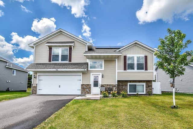 39604 Fallbrook Ave, North Branch, MN 55056 - view of front facade featuring a garage, stone siding, roof mounted solar panels, and a front lawn