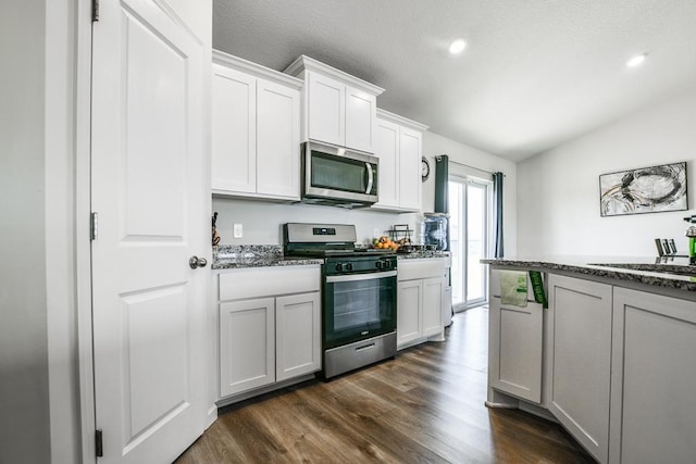 39604 Fallbrook Ave, North Branch, MN 55056 - kitchen with appliances with stainless steel finishes, dark wood-type flooring, vaulted ceiling, white cabinets, and dark stone counters