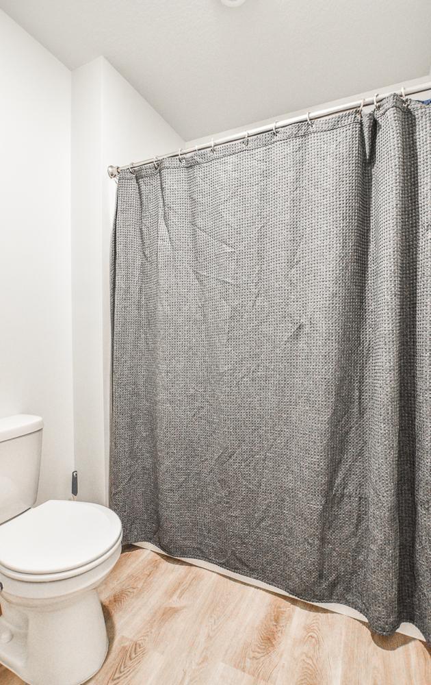 39604 Fallbrook Ave, North Branch, MN 55056 - full bathroom with wood finished floors and a shower with shower curtain