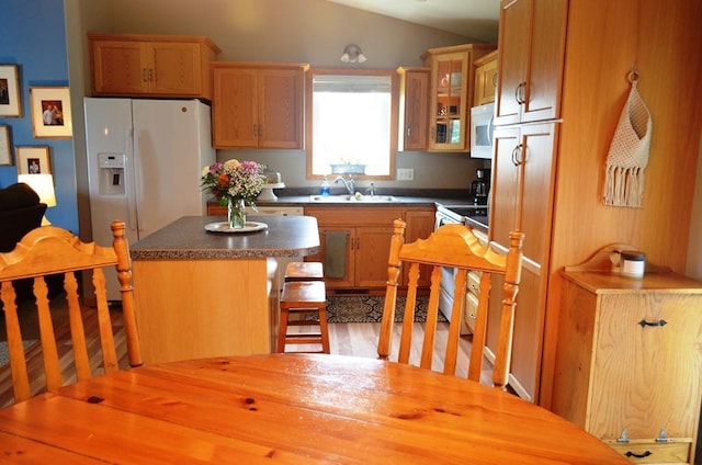 1120 Madisson St, Alexandria, MN 56308 - kitchen featuring white appliances, a kitchen island, vaulted ceiling, dark countertops, and glass insert cabinets