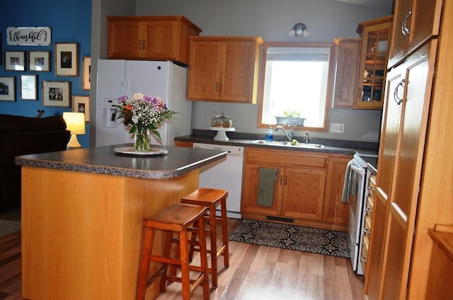 1120 Madisson St, Alexandria, MN 56308 - kitchen with white appliances, light wood-type flooring, dark countertops, glass insert cabinets, and a center island