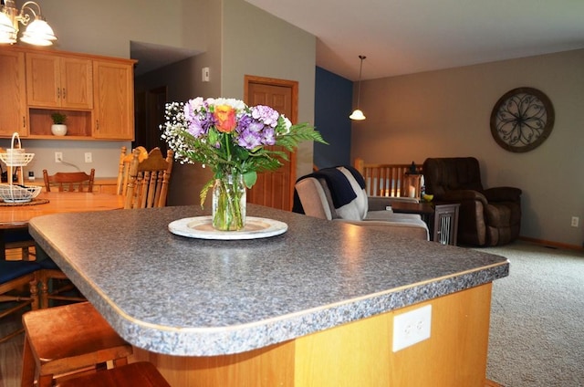 1120 Madisson St, Alexandria, MN 56308 - kitchen with a kitchen island, lofted ceiling, carpet, a breakfast bar, and dark countertops