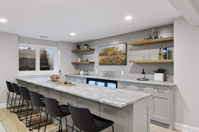 2462 Lafayette Rd, Minnetonka Beach, MN 55391 - kitchen with open shelves, light wood-style floors, a breakfast bar area, light stone countertops, and recessed lighting