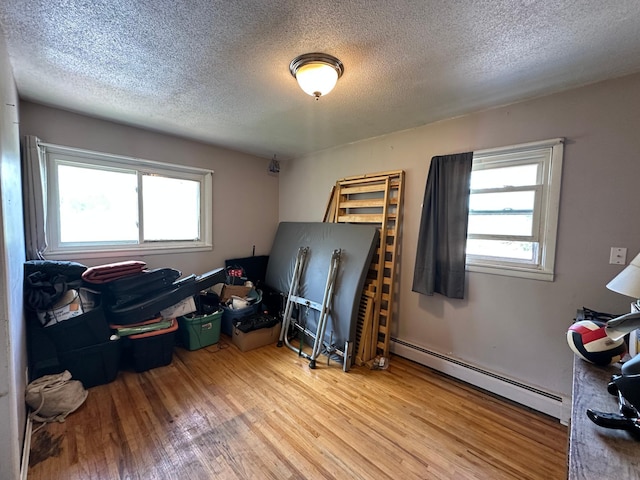 402 Grouse St, Sandstone, MN 55072 - miscellaneous room featuring a baseboard heating unit, wood finished floors, and a textured ceiling